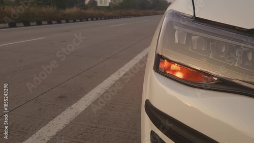 Glowing amber indicator light on a car during sunset creates a dramatic automotive visual while representing transportation safety and vehicle signaling.