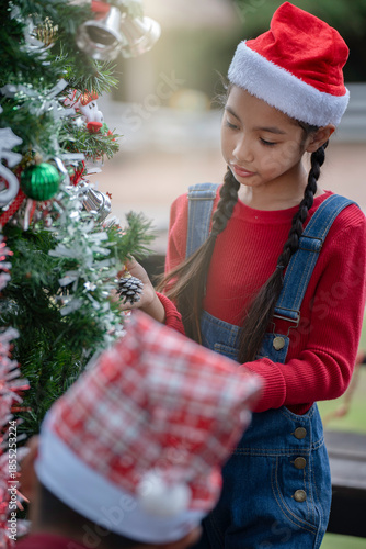 The children are celebrating Christmas and decorating the Christmas tree together.