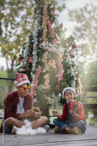 The children are celebrating Christmas and decorating the Christmas tree together.