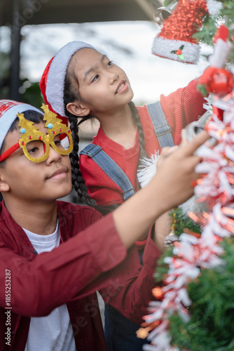 The children are celebrating Christmas and decorating the Christmas tree together.
