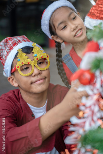 The children are celebrating Christmas and decorating the Christmas tree together.
