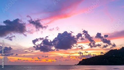 Vibrant sunset over ocean horizon with colorful clouds and mountain silhouette scenic landscape