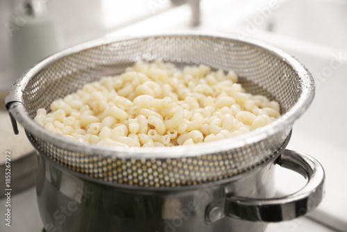 Obraz na płótnie Sieve with pasta on pot in kitchen, closeup