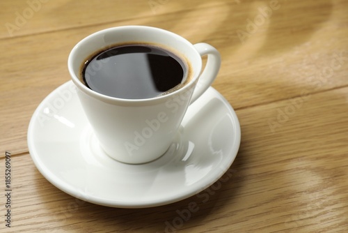 Aromatic coffee in cup on wooden table, closeup