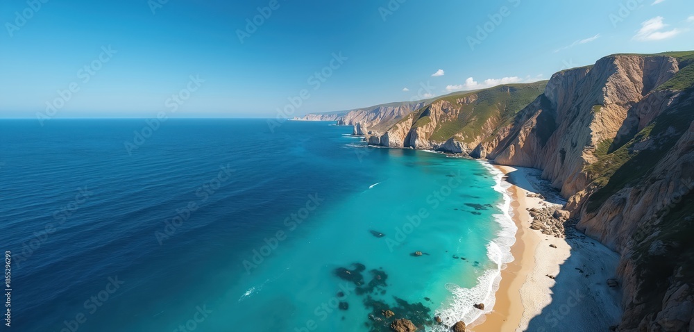 Fototapeta premium Stunning aerial view of a tropical coastline with sheer cliffs meeting clear turquoise ocean waters and a sandy beach below. Lush green vegetation covers cliff tops under a bright blue sky.