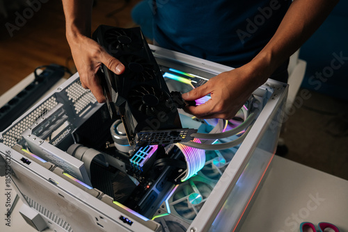 Canvas Print Skilled computer professional inserting high-performance graphics card into custom gaming pc, illuminating interior with vibrant RGB lighting for enhanced visual experience