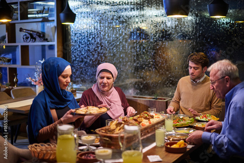 Muslim family enjoying iftar meal in a restaurant with Ramadan decorations during evening hours