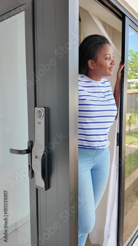 Lilongwe Malawi Africa, 01.12.2025. Video.. Woman standing and looking out of a patio door in a country garden. Malawi Africa.