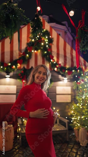 Pregnant lady dressed in scarlet ambles peacefully amidst holiday decorations and twinkling lights slow motion