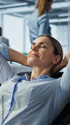 A  businesswoman sits in an office chair with her eyes closed and her hands resting behind her head