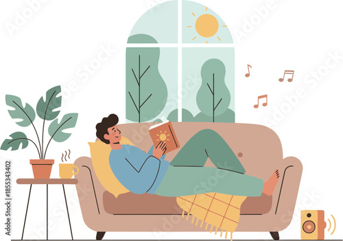 Young man relaxing on a comfortable couch reading a book and listening to music.