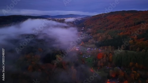 village lights glow through morning mist, serene scene of foggy valley during sunrise and blue hour
