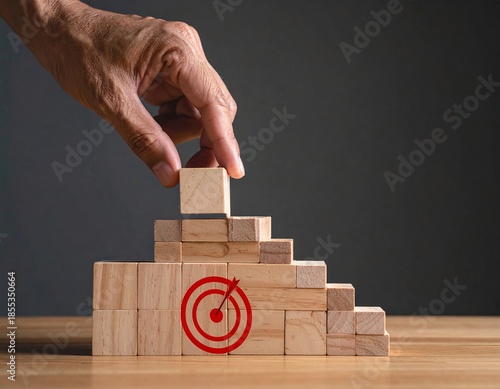 a hand reaching for a wooden block structure with a red target symbol on it