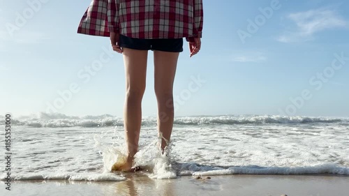 Barefoot person walking along sandy beach shoreline, slow motion steps near ocean waves, calm summer mood, relaxation, freedom, travel lifestyle, minimal seaside scene