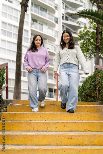 Young women walking downstairs outdoors talking looking happy
