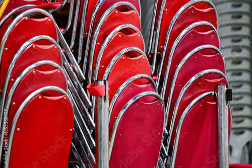 Red velvet chairs with chrome frames organized and stacked for storage, event preparation concept.
