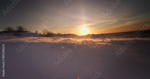 Frozen landscape of snow covered field after a blizzard, ice desert, winter wonderland, wind blows snowflakes, morning sunlight, polar sunrise 4K cinematic video