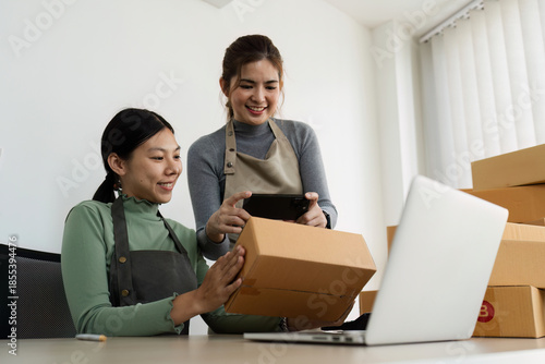 Asian woman using laptop to prepare for delivery to customer. e-business concept