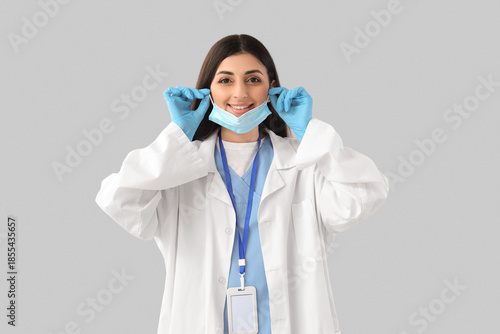 Female doctor with medical mask and gloves on light background. Immunity concept