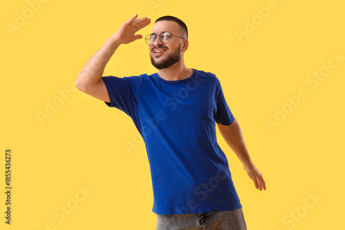 Young man looking at something on yellow background. Search concept