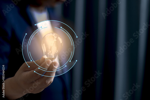 Person holding glowing light bulb with digital elements surrounding it, symbolizing innovation and technology. image conveys futuristic and creative concept