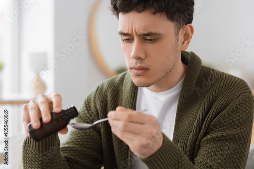 Ill young man pouring cough...