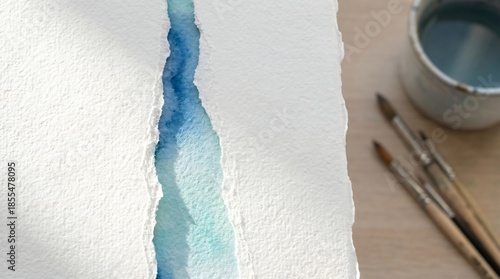 Watercolor painting setup with brushes and palette on wooden table