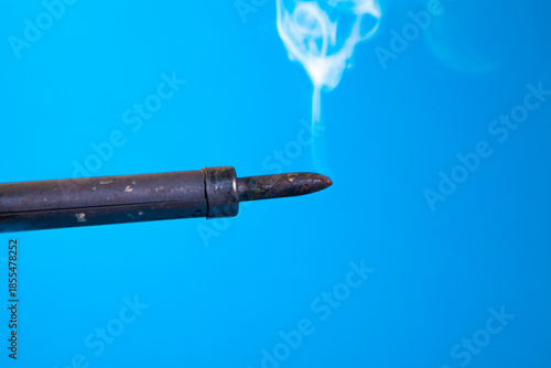 Smoke coming out of a gun tip on a blue background.