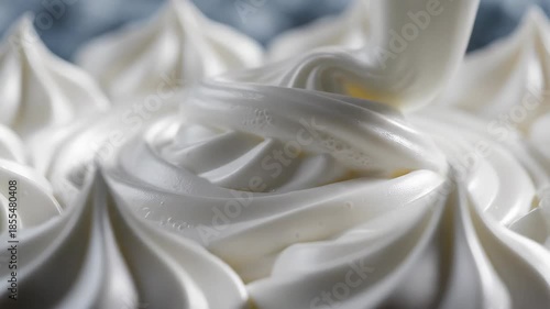Closeup view of delicate white meringue or whipped cream swirls expertly piped and arranged showcasing a soft creamy texture perfect for sweet desserts and confectionery creations.