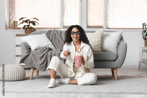 Beautiful young African-American woman in 3D glasses with bucket of tasty pop...