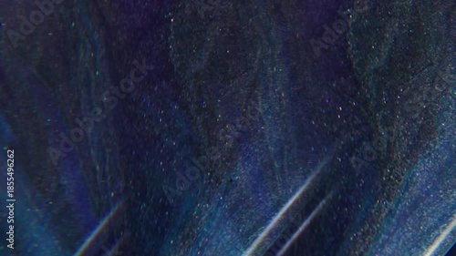 Shiny paint. Neon background. Defocused purple silver blue colorful glitter flow particles spreading on geometric acrylic abstraction.