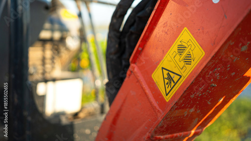 Safety caution sign on the backhoe front part, instruciton for keep out from the swing radius to prevent the accident. Safety sign on the industrial machine, close-up.