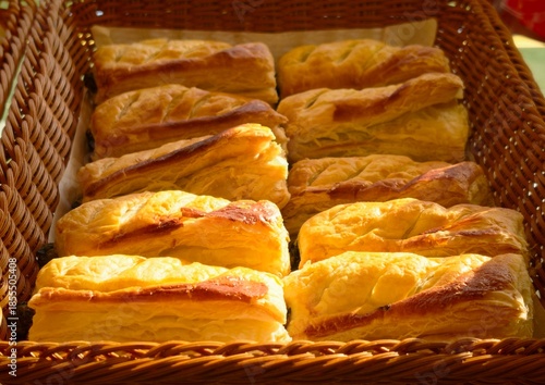Freshly baked puff pastries arranged in wicker baskets at a bakery display. Golden, flaky layers and warm lighting create an inviting atmosphere, highlighting freshness and quality. Suitable for baker