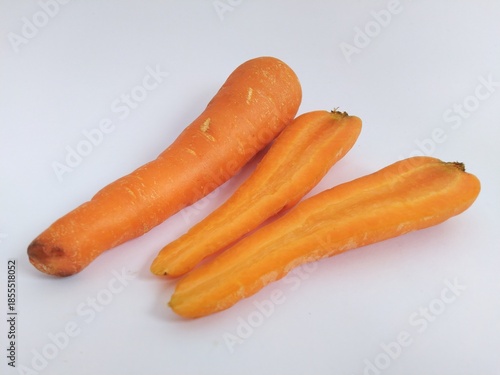 Fresh whole carrot and halves of carrot showing the vibrant orange interior texture, isolated on a clean white background