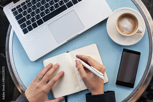 new year resolutions writing, intentions, female hands with paper notepad, pen, smartphone and laptop computer