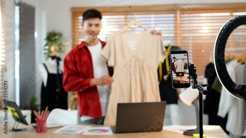 Obraz na plátně Asian man selling clothes and accessories online by smartphone live streaming, b