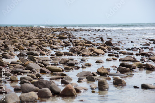 Rocks/stones on the  beach during a daylight on the islands, Thailand.Background image of the beach with sea in the distance with pebble stones.