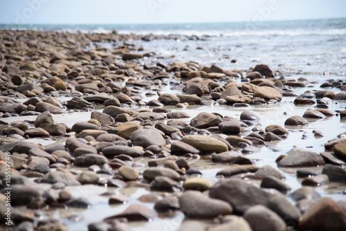 Rocks/stones on the  beach during a daylight on the islands, Thailand.Background image of the beach with sea in the distance with pebble stones.