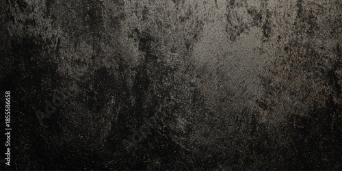 A dark textured surface presenting a mottled pattern of grays and blacks reminiscent of distressed concrete or aged metal