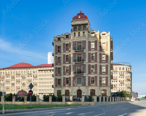 Elegant building with red roof and turret, on 8 November Ave, Baku, Azerbaijan. Distinctive architecture with a red pointed roof, ornate facade, and balconies under a clear blue sky