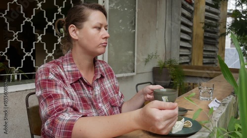 Sitting in a cafe, a woman drinks coffee and eats a soft plum cream matcha cake as if on vacation, savoring flavors while embracing a slow carefree lifestyle. Simple pleasure.