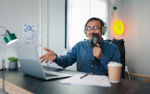 Smiling man in headphones recording podcast in studio with microphone, enjoying conversation and audio production 
