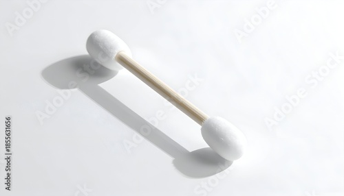 A close-up, top-down view of a cotton swab, its shadow cast on a white surface
