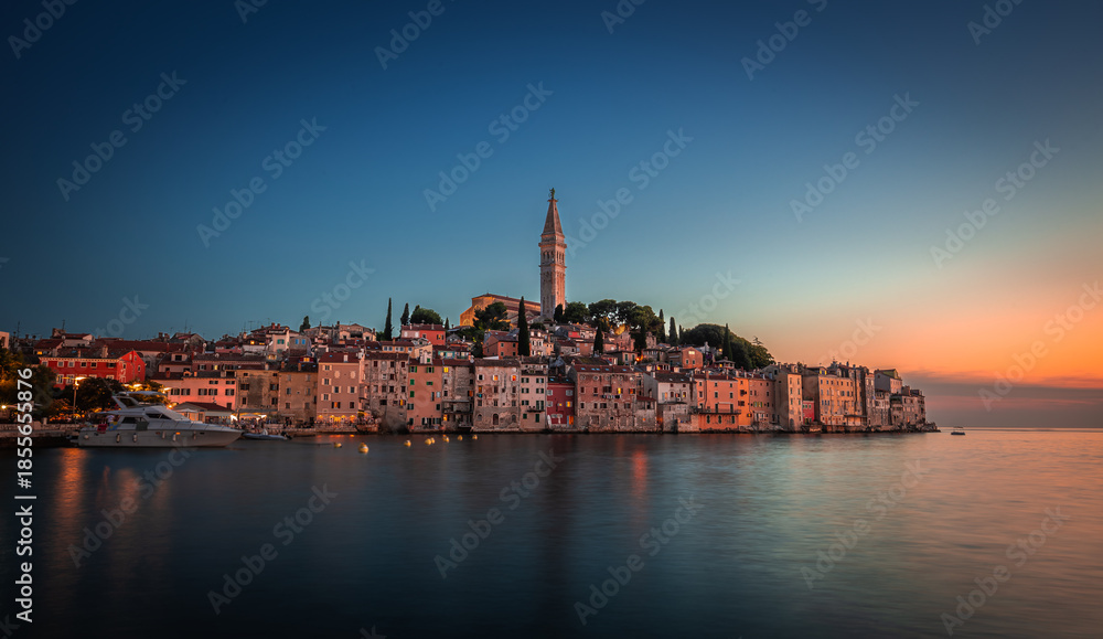 Fototapeta premium Rovinj, Croatia - Sunset view of beautiful Old Town of Rovinj with the tower of Saint Euphemia church in Adriatic sea coast. Clear blue sky, golden sunset colours