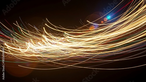 Vibrant golden light trails create a mesmerizing abstract pattern against a dark background, evoking a sense of speed, digital connectivity, and futuristic energy
