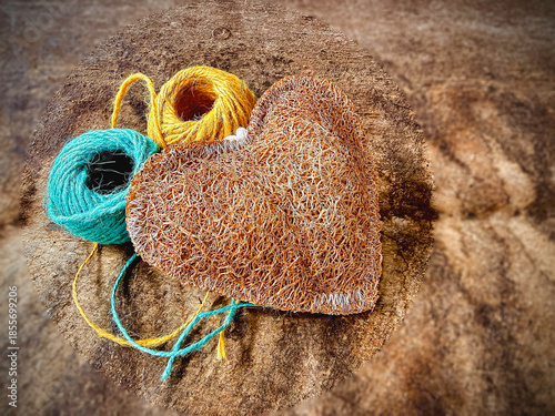Single Luffa heart shape,texture is coarse and fibrous.put on vintage wooden board,blurry light around