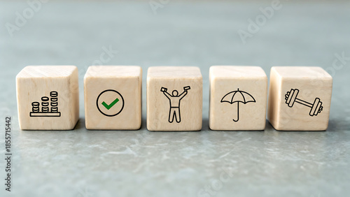 Five wooden blocks with icons representing savings, success, achievement, protection, and health on a textured surface.