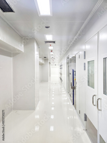 Konstfotografi A long, clean, white corridor with doors on the right side and lights on the ceiling