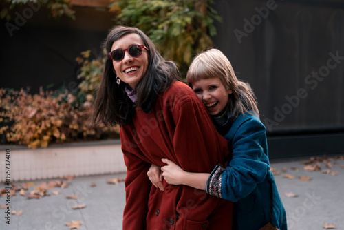 Happy mother and daughter having fun together and hugging outdoors in city