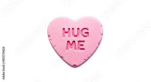 Pink heart shaped candy with the words Hug Me embossed on it against a black background love